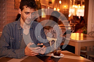 Unshaven millennial with cellphone in restaurant