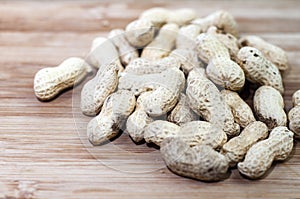 Unshelled monkey nuts on a wooden background