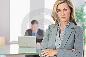 Unsmiling businesswoman looking at camera crossed arms with a bu