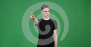 Unsmiling caucasian man shaking his finger in denial against green background