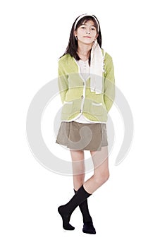 Unsmiling confident young girl in green sweater standing, isolated photo