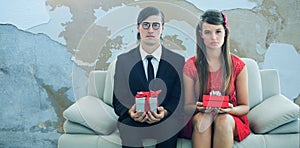 Composite image of unsmiling geeky couple with gift photo