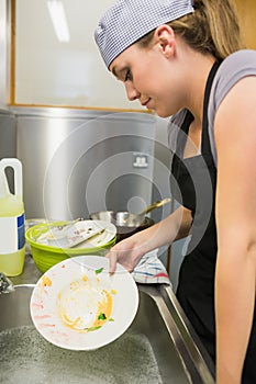 Unsmiling woman washing a plate