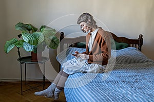 Unsociable teen girl sitting on bed with smartphone, scrolling, feeling lonely, rejected, unhappy photo