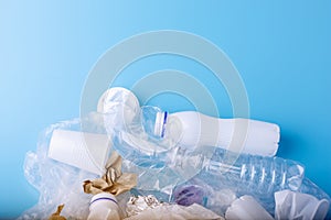 Unsorted clean garbage in a pile. Bottles, bags and paper on blue background. Environmental pollution and waste sorting
