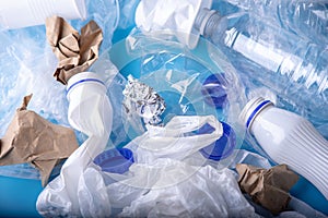 Unsorted clean garbage in a pile. Bottles, bags and paper on blue background. Environmental pollution and waste sorting