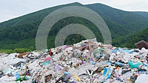 An unsorted garbage dump in the middle of a green forest in the mountains.