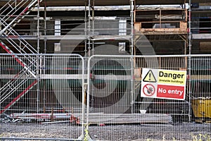 Unstable building keep out dangerous sign on fence at building construction site