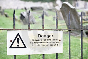 Unstable headstones memorials at burial ground gravestones danger sign photo