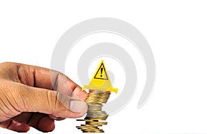 Unstable pile of coins and Warning label on whitebackground