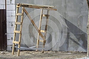 Unstable wooden trestles on the background of a gray wall