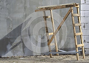 Unstable wooden trestles on the background of a gray wall.