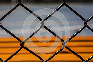 Unstoppable warm color, orange-red bench by the open-air cement basketball court inside the barbed wire