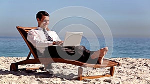 Unstressed businessman using laptop on the beach