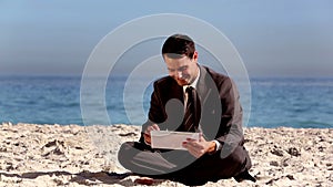 Unstressed businessman using tablet pc on the beach