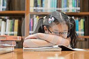 Unsuccessful educational system concept with Asian child girl student getting bored reading book in school classroom library