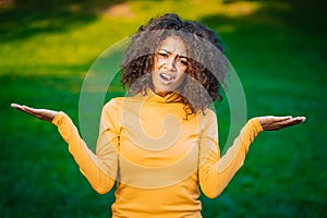 Unsure african american woman shrugs her arms, makes gesture of I don`t know, care, can`t help anything . Mixed race