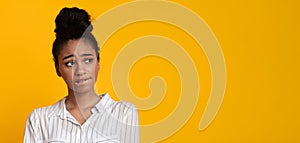 Unsure Afro Girl Looking Aside At Copy Space Over Yellow Background photo