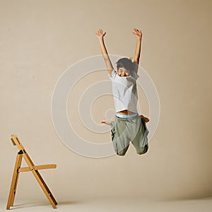 Unsure indian boy jumping up, bending knees and throwing hands up in the air