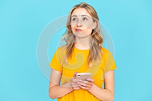 Unsure woman holding smartphone and hesitate about buying things online photo