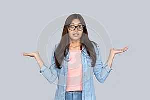 Unsure young indian woman shrug shoulders look at camera on grey background