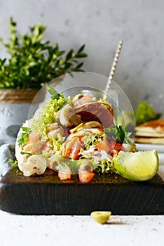 Unsweetened pancakes with turkey, lettuce, tomatoes, pickled mushrooms, olives and greens in the form of tacos on a wooden board.