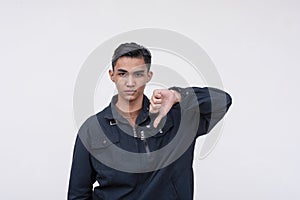A unsympathetic young Filipino man turning down an offer, giving the thumbs down. Isolated on a white background