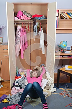 Untidy teenage girl lying on pile of clothes photo