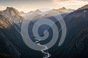 Majestic mountain range in evening light, featuring snow-capped peaks and rugged cliffs.AI