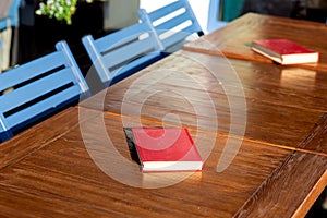Untitled red hardcover book on a wooden brown table.