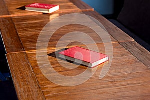 Untitled red hardcover book on a wooden brown table.