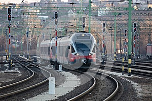 Untitled red passenger train arrival at railway train station. Platform track front view.