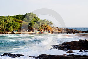 Untouched tropical beach with rocks in the water and white waves in Sri Lanka