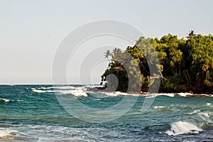 Untouched tropical beach with rocks in the water and white waves in Sri Lanka