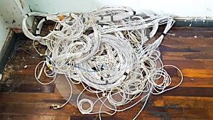 Unused bundles of old LAN cable wires on brown wooden floor