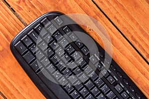 Unused new black pc keyboard above wooden planks background