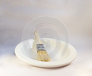 an unused paint brush on a clean white plate