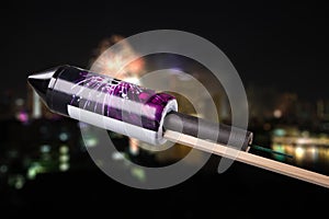 Unused pyrotechnics rocket in front of a blurry city with fireworks explosion photo