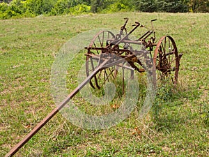 Unused and rusted farm plow in field