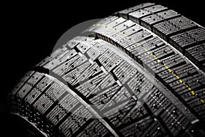 Unused winter car tire on a black background. photo