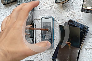 An unusual background of broken phones nailed to the wall. An evil man breaks phones with a nail and nails them to the wall.