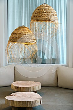 Unusual designer chandeliers made of straw. A spacious and cozy living room with upholstered sofas, wooden tables and panoramic