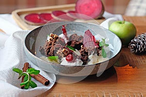 An unusual dessert in a plate of torn sponge cake, beetroot slices, nuts with apple and mint leaves