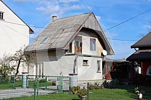 Unusual looking small suburban family house with wooden front porch and tall pointy roof surrounded with large family houses