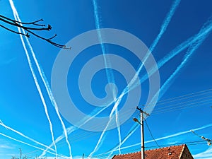 Unusual pattern of airplane condensation trails across the blue sky photo
