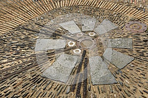 Unusual pavement with creative pattern from metal details, sea pebbles, bricks; ceramic, granite