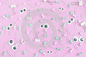 An unusual picture with scattered stationery. Funny faces with puppet eyes. Clips, clerical buttons and asterisks in a