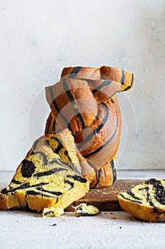 Unusual pumpkin marbled tiger print bread with cuttlefish ink, braided on a wooden board on a light background.