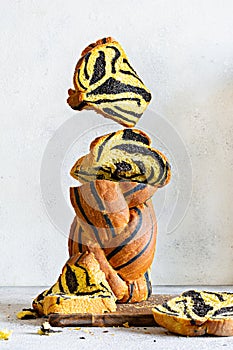 Unusual pumpkin marbled tiger print bread with cuttlefish ink, braided on a wooden board on a light background.