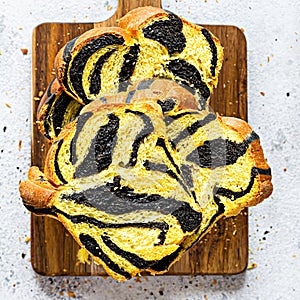 Unusual pumpkin marbled tiger print bread with cuttlefish ink, braided on a wooden board on a light background.